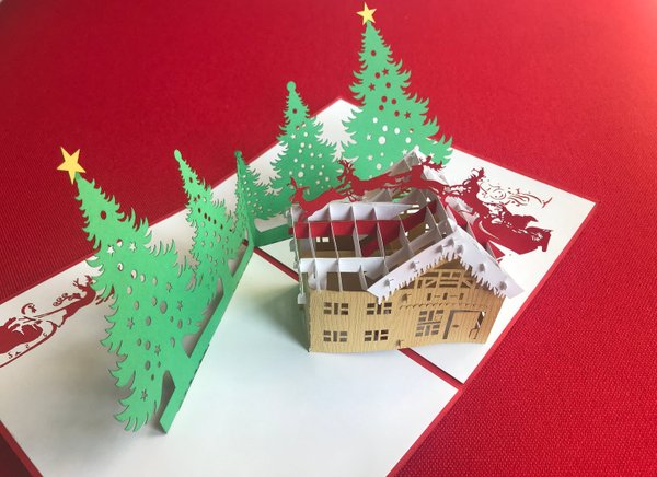 Weihnachtskarte mit Haus, Bäumen und Rentieren